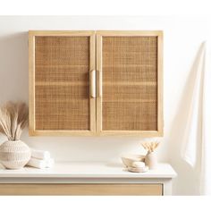 a wooden cabinet sitting on top of a white counter next to a vase and towel