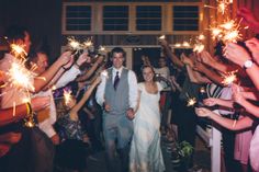 a bride and groom are surrounded by sparklers as they walk down the aisle at their wedding