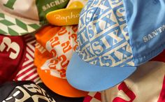 many hats are stacked on top of each other in different colors and patterns, including blue, green, yellow, red, orange