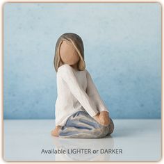 a small doll sitting on the ground with her legs crossed and head turned to the side