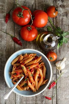 a bowl filled with pasta next to tomatoes