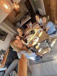 a group of women sitting at a table eating food and drinking coffee in a kitchen