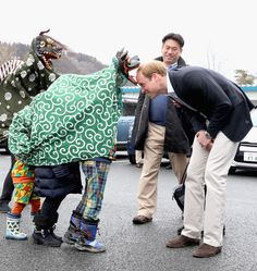 some people are standing around and looking at a fake dragon on the street while others look on