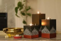 three candles sitting on top of a wooden table next to a bowl and candle holder