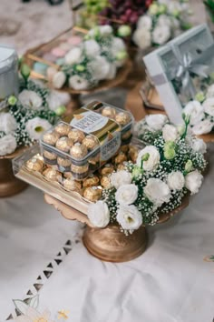 a table topped with lots of trays filled with chocolates and flowers on top of it