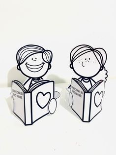 two paper cut out of people reading a book with hearts on their heads and one holding a heart