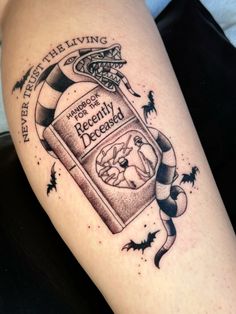 a tattoo on the leg of a woman with a bottle of booze and bats around it