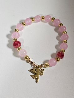 Add a touch of romance to your jewelry collection with this enchanting bracelet. Crafted with delicate pink and gold beads, it exudes a soft, feminine charm. The centerpiece is an adorable cupid charm, symbolizing love and affection. This bracelet is perfect for special occasions or as a heartfelt gift for someone special. Its elegant design makes it a timeless piece that will be cherished for years to come. Luxury Pink Gold Bracelets As Gift, Pink Charm Bracelet, Gold Arm Band, Gold Bead Bracelet, Gold Armband, Gold Bead Bracelets, Soft Feminine, Love And Affection, Heartfelt Gifts