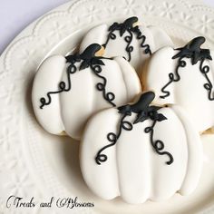 four decorated cookies sitting on top of a white plate covered in icing and black decorations