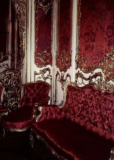 an ornately decorated living room with red velvet couches