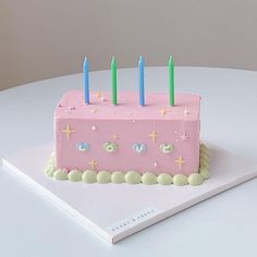 a pink birthday cake sitting on top of a white table