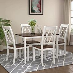 a dining room table with white chairs and a potted plant on the rug in front of it