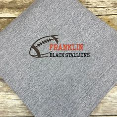 the franklin black stallions logo on a gray t - shirt with an orange football