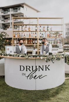 two men standing behind a bar that says drunk in love