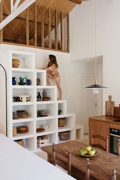 a woman standing on top of a white book shelf