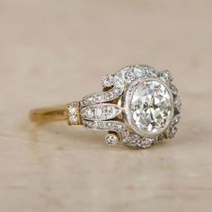 an antique style diamond ring on a wooden surface with the center stone surrounded by smaller diamonds