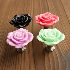 three different colored roses are sitting on a wooden table with metal knobs in the shape of flowers