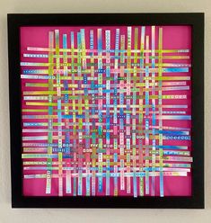 a pink and black framed art piece with strips of colored tape on the bottom half of it