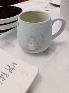 two mugs sitting on top of a table next to each other with writing on them