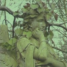 a statue with leaves on it's head is sitting in front of some trees