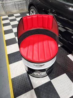 a black car parked in a garage next to a red and white checkered floor