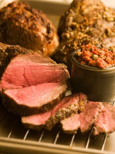 a close up of some meat on a plate with a bowl of food in the background