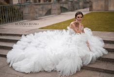 a woman is sitting on some steps in a white wedding dress and posing for the camera