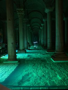 the inside of an old building with columns lit up in green and blue lights at night