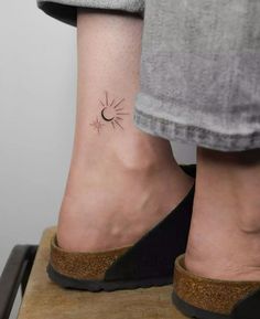 a woman's foot with a small sun tattoo on it