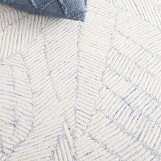 a blue and white rug on the floor next to a pillow, blanket and pillows