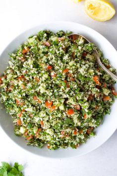 a white bowl filled with chopped vegetables on top of a table next to a spoon