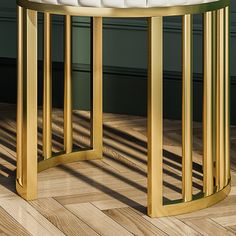 a gold and white round table sitting on top of a hard wood floor