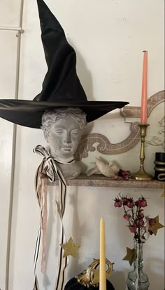 a witch's hat sits on top of a shelf next to candles and other decorations