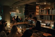 a group of people sitting at a bar in a room with record players and records on the shelves