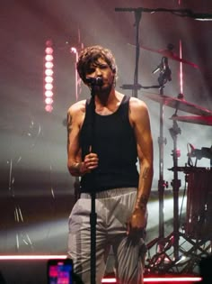 a man standing on top of a stage holding a microphone in front of his face