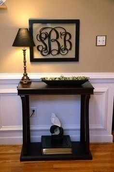 a table with a lamp on top of it next to a framed monogramm