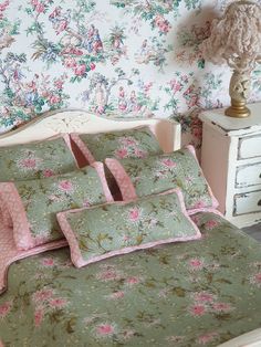 a bed with pink and green floral bedspreads