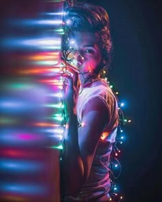 a woman standing next to a wall covered in christmas lights