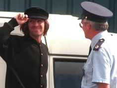 a man in uniform saluting another man with his hand on his hat while standing next to a white truck