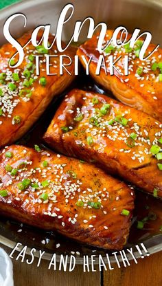 salmon teriyaki in a pan with sesame seeds and green onions on the side