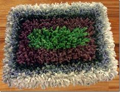 a close up of a rug on top of a wooden floor with a green plant in the center