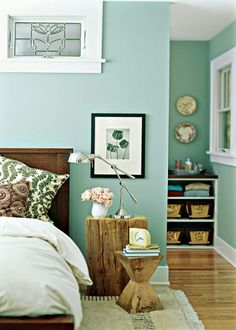 a bed room with a neatly made bed next to a window and pictures on the wall