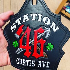 a person holding up a black leather badge that says station 46 curtis avenue on it