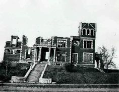 an old building with stairs leading up to the front door and windows on top of it