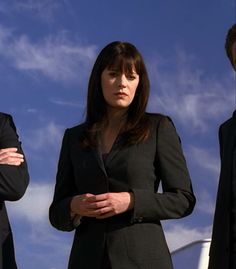 three business people standing next to each other in front of a blue sky with clouds