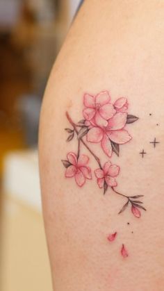 the back of a woman's thigh with pink flowers and stars tattooed on it