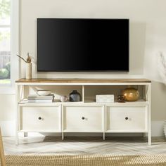 a flat screen tv sitting on top of a white entertainment center next to a window