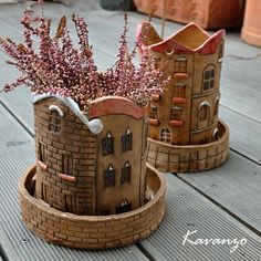 two clay pots with flowers in them sitting on a wooden table next to each other