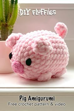 a pink crochet pig sitting next to a potted plant