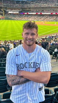 a baseball player is posing for a photo in the stands at a stadium with his arms crossed